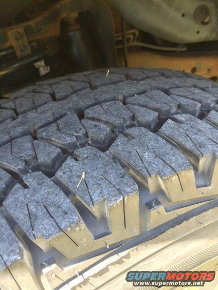 Close-up of a tire tread with visible wear and some debris