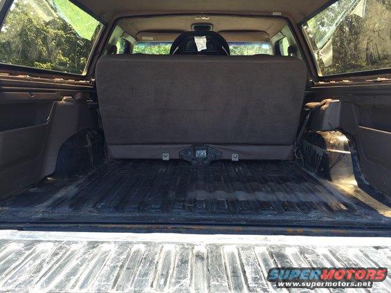 SUV cargo area with folded rear seats, tow hitch visible, trees outside