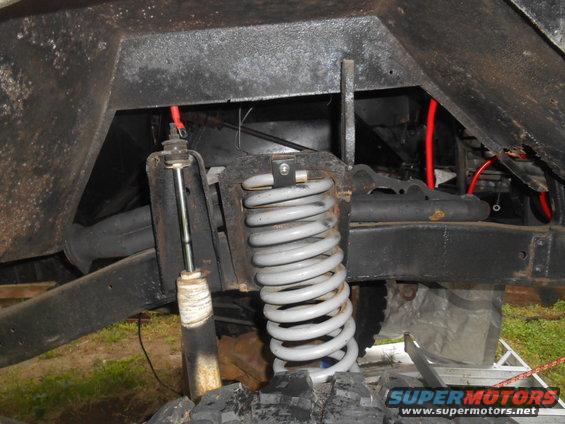 Close-up of a vehicle's front suspension with a coil spring and shock absorber visible