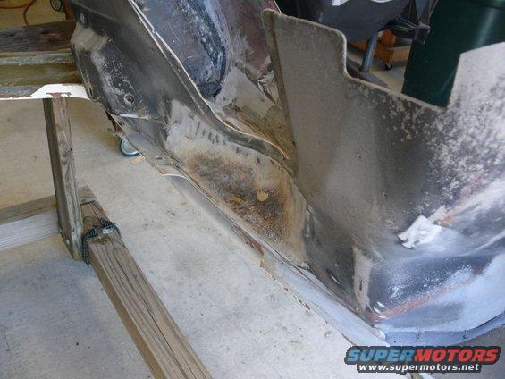 rusted car frame section on wooden support
