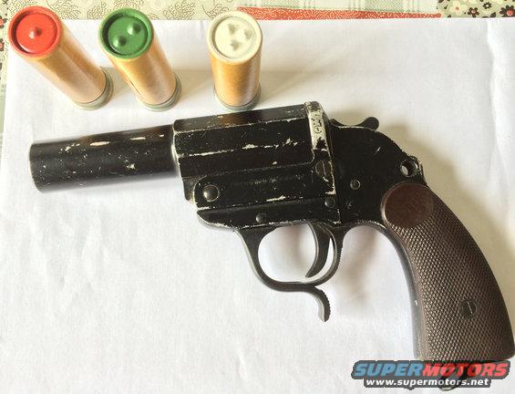 Black flare gun with worn paint and three cartridges (red, green, white-tipped)