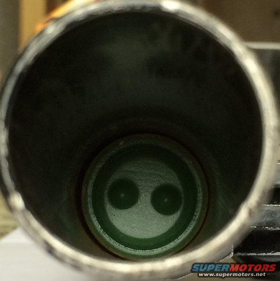 Interior of an exhaust pipe showing a green fitting with two circular openings