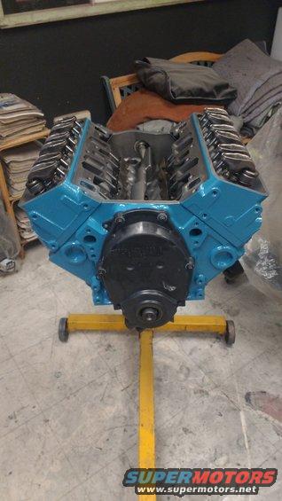 Blue V8 engine on a yellow stand, front view