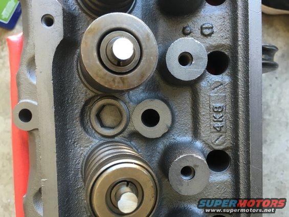Engine cylinder head with visible valve springs and bolts. Stamped '4K8'
