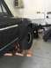 1979 Ford Bronco - A black SUV's fender and tire are elevated on jack stands in a garage, revealing its side profile and suspension.