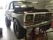 1979 Ford Bronco - A 1979 Ford Bronco is shown with its front end elevated on jack stands, undergoing maintenance with the hood open.