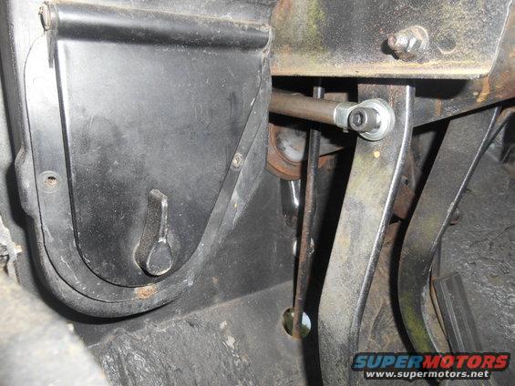 Close-up of vehicle's clutch, brake, and gas pedals, with linkage visible