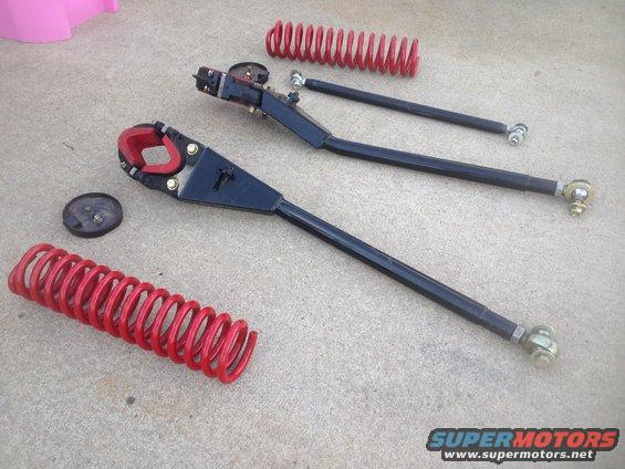 Red coil springs and black suspension control arms with red rubber bushings on concrete