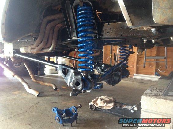 Underside of a 1978 Ford Bronco with bright blue suspension components and exhaust pipes