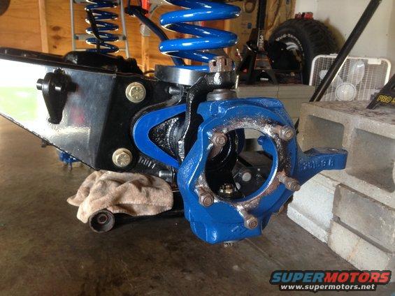 Close-up of a blue-painted vehicle suspension component with a coil spring