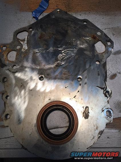 Engine timing cover with oil seal, metal surface showing wear and damage