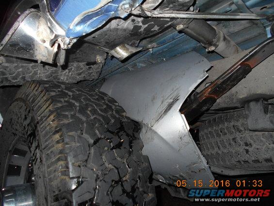 Close-up of truck underbody showing tire, suspension, and body panel damage