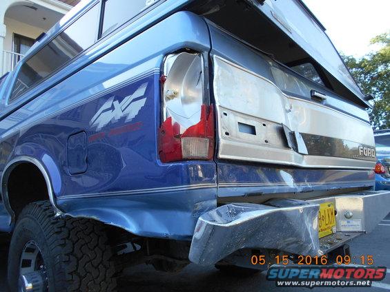 Rear view of blue 1996 Ford F-250 with damaged taillight and camper shell