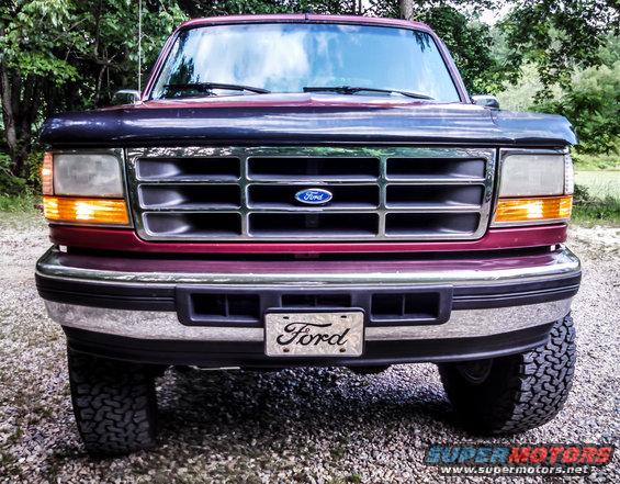 Maroon Ford Bronco front view, showing grille and headlights. Tires are visible
