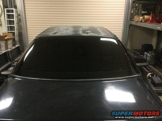Rear of black sedan with tinted windows and peeling paint on the roof