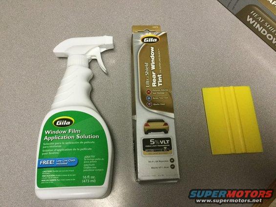Bottle of Gila window film application solution, box of Gila Ultra-Shield Rear Window Tint, and a yellow squeegee tool