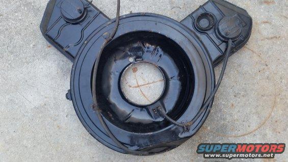 Black air cleaner assembly with two circular lids on top, resting on concrete