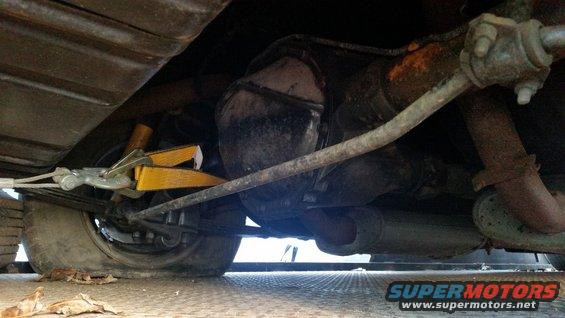 Undercarriage view with yellow jack stand supporting rear axle