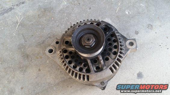 Used alternator with pulley, resting on concrete