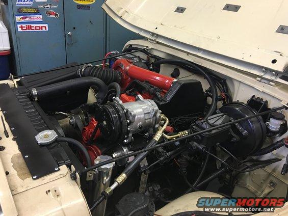 Cream-colored Jeep engine bay with a red intake manifold and silver air conditioning compressor