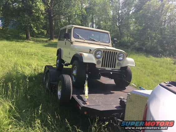 Tan Jeep CJ-5 on a flatbed trailer, front view