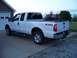 2011 Ford F-250 - This white 2011 Ford F-250 pickup truck is shown from the rear 3/4 angle, parked in a driveway.
