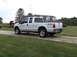 2011 Ford F-250 - A white 2011 Ford F-250 truck is parked on a gravel driveway in front of a house.
