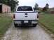 2011 Ford F-250 - White 2011 Ford F-250 Super Duty pickup truck seen from the rear on a gravel driveway.