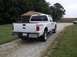 2011 Ford F-250 - This white Ford F-250 Super Duty pickup truck is parked on a gravel driveway next to a grassy area and a building.