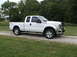 2011 Ford F-250 - This white Ford F-250 Super Duty pickup truck is shown from the front three-quarter view on a gravel driveway.