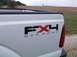 2011 Ford F-250 - Close-up of the FX4 OFF ROAD decal on the rear of a white pickup truck.