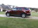 2016 Ford Explorer - A maroon Ford Explorer is parked on a gravel driveway in front of a house.
