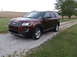 2016 Ford Explorer - A maroon Ford Explorer is parked on a gravel driveway with fields and trees in the background.