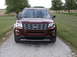 2016 Ford Explorer - This 2016 Ford Explorer is shown from the front, parked on a gravel driveway with grassy fields and trees in the background.