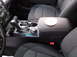2016 Ford Explorer - The interior of a vehicle shows the center console area with a gear shifter and armrest. A white disc is placed on the armrest.