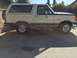 1990 Ford Bronco - A side view of a white 1990 Ford Bronco shows its classic body style and spare tire mounted on the back.