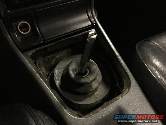 car's center console with gear shifter and boot removed, showing the shifter rod