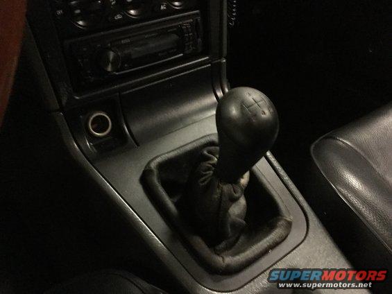 Black leather gear shifter and center console with a cigarette lighter port and car stereo