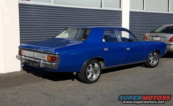 Blue sedan's rear 3/4 view with chrome wheels and a license plate reading JE 1748