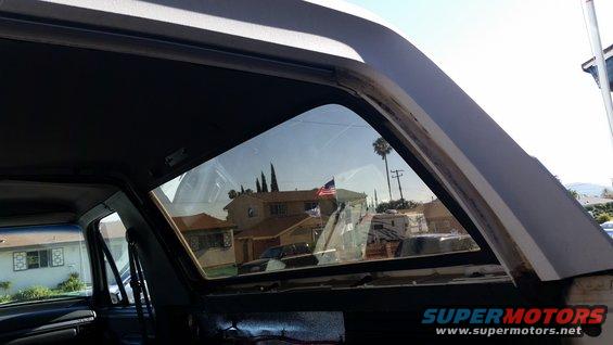 Interior of a vehicle looking out a window at houses and an American flag