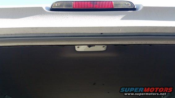 Interior view of a vehicle's rear cargo area, showing the upper trim and third brake light