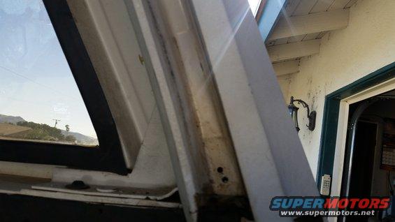 Close-up of a vehicle's door frame and window seal, showing some wear and tear
