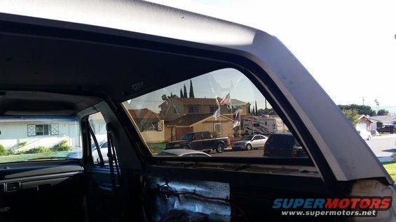 View from inside a vehicle looking out the side window at houses, a pickup truck, and a sedan