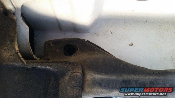 Close-up of a metal bracket on a vehicle's frame with a bolt hole