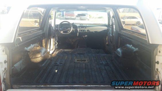 Interior of an empty SUV, showing the dashboard, steering wheel, and cargo area. The seats and carpeting are removed