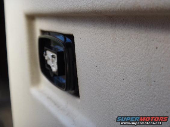 Close-up of a black switch on a beige interior door panel