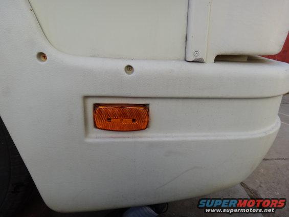 Orange reflector light on white vehicle bumper