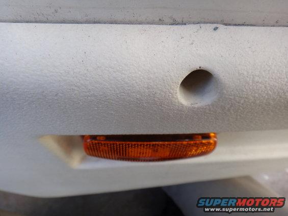 Close-up of an orange marker light on a vehicle's body. There's a hole above it