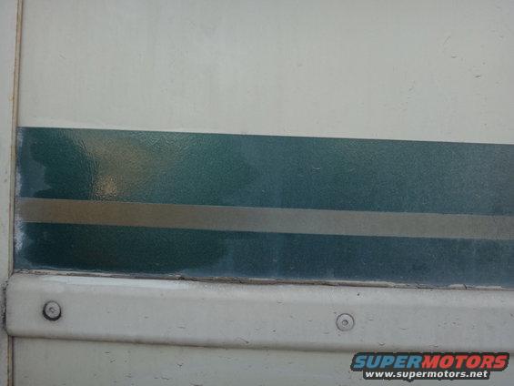 Vehicle side panel with a dark green stripe and a thin gold stripe above a white trim piece