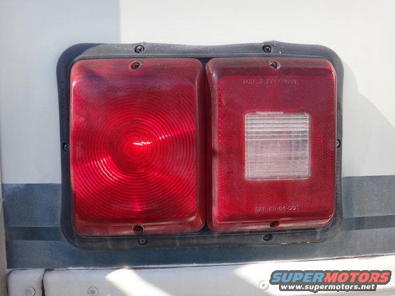 Taillight assembly with red and clear lenses, mounted on a white vehicle